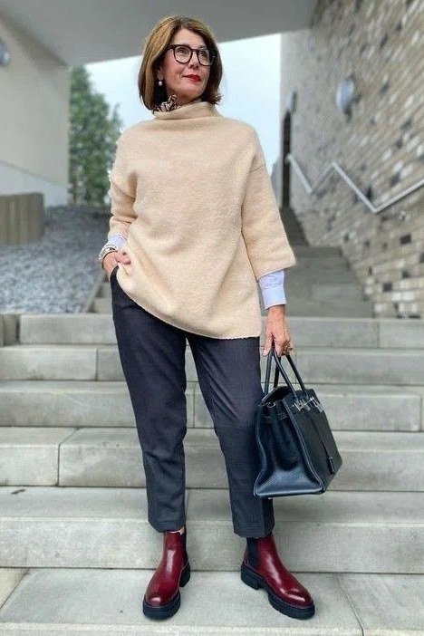 Beige poncho, dark slim pants, burgundy ankle boots, woman on stairs