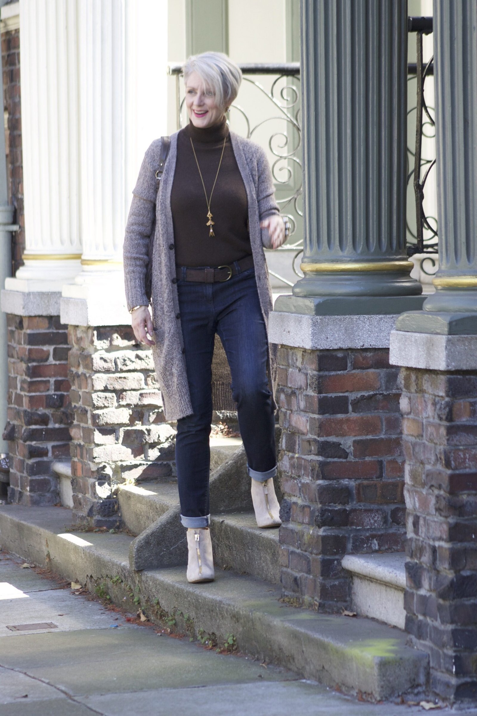 Gray cardigan, black turtleneck, dark jeans, white sneakers, mature woman