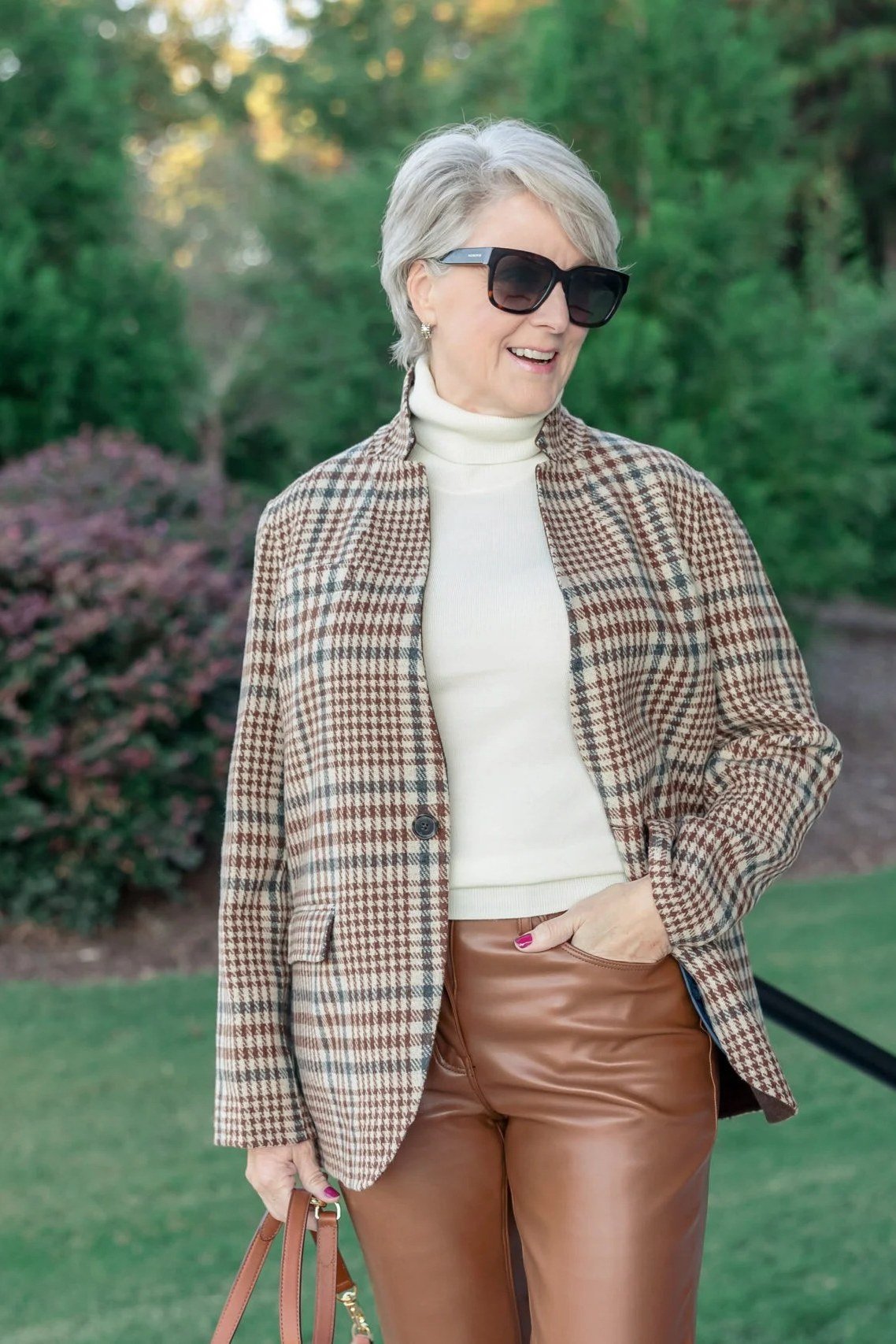Brown plaid blazer, white turtleneck, brown leather pants, woman in garden