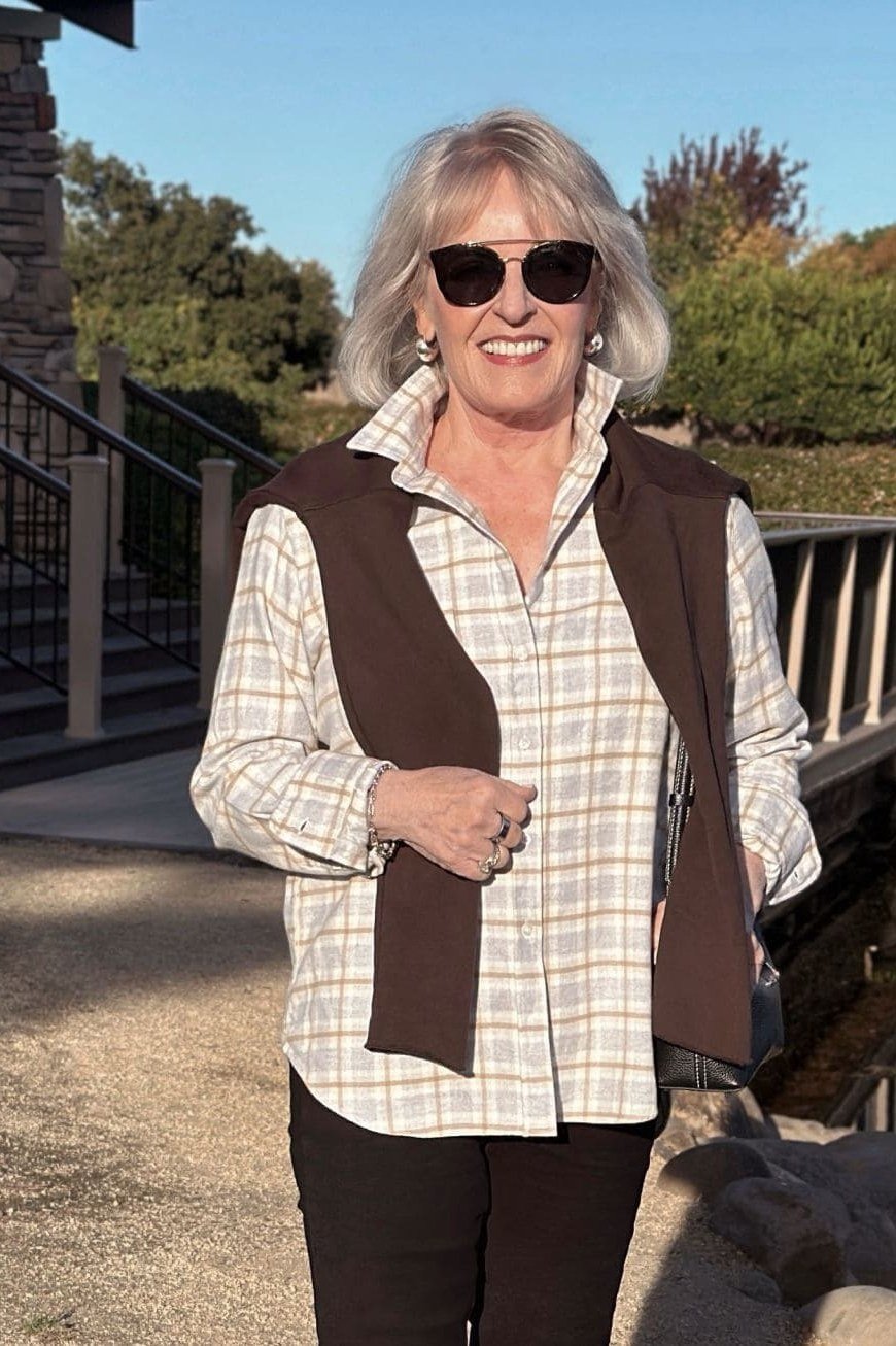 Cream plaid shirt, brown knit vest, dark pants, woman on deck