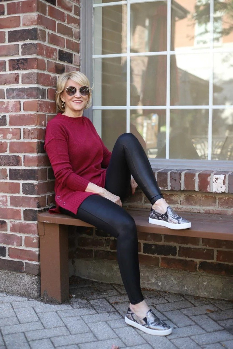 Red sweater, black leggings, gray sneakers, woman sitting on bench