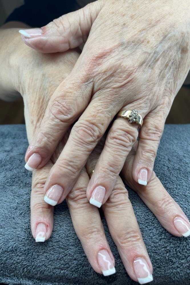 Classic white-tip french manicure on older hands with a blue towel