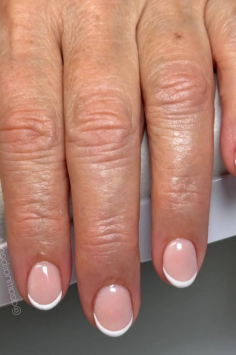 Closeup of a glossy pink french manicure