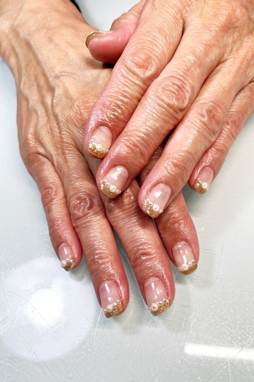 Elderly hands with gold glitter french tips