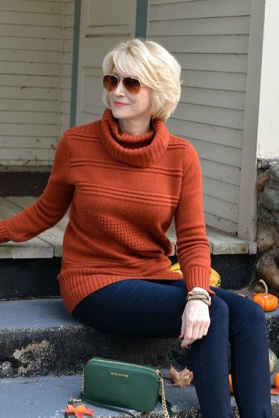 Fall sweater outfit idea 5 for women over 60: burnt orange turtleneck with navy pants