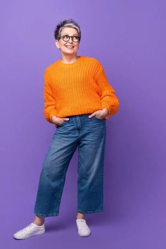 Fall sweater outfit idea 21 for women over 60: orange sweater with wide blue jeans
