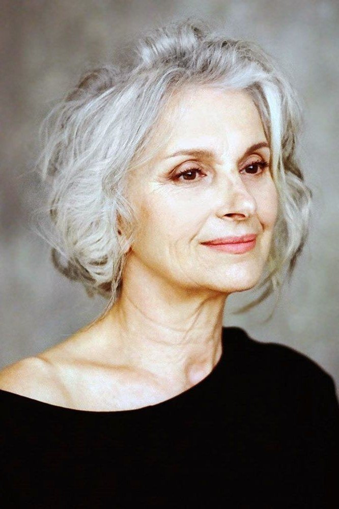 Short white wavy bob haircut, front view of older woman in black top