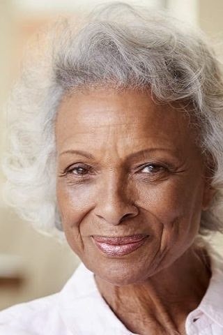 Short curly white bob with natural curls on older Black woman, front view