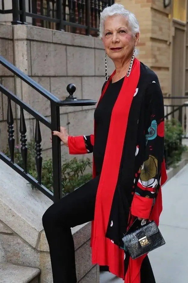 Senior woman in black top, red scarf and black pants on stairs