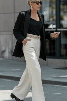 Senior woman in black blazer, black top and white wide pants