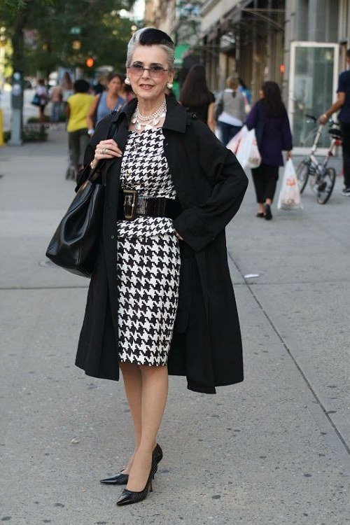 Older woman in black coat and houndstooth dress on the street