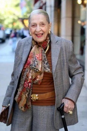 Older woman in gray blazer, rust top and printed scarf on the street