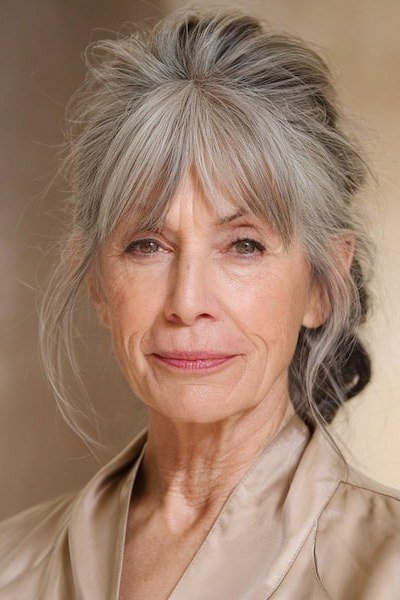 Elegant Silver Updo with Wispy Face-Framing Bangs for women over 60, grey hairstyle with bangs
