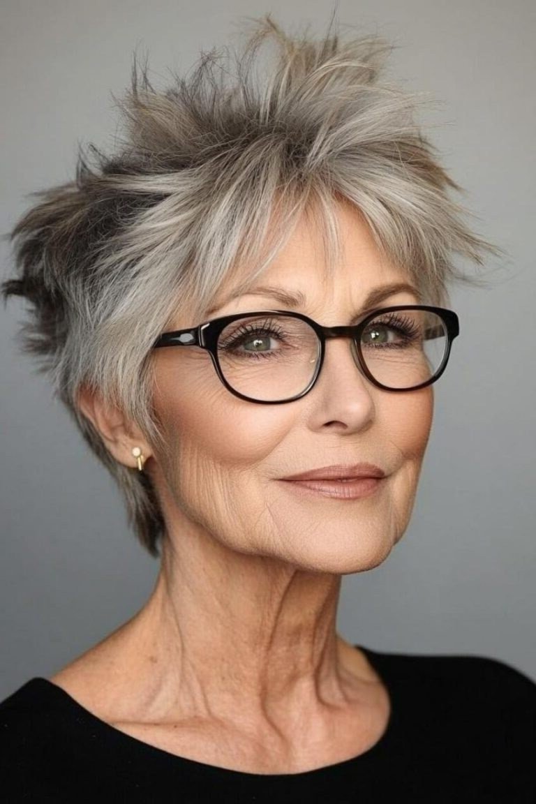 Grey pixie haircut for women over 50: silver spiky pixie with glasses, front view, dark background