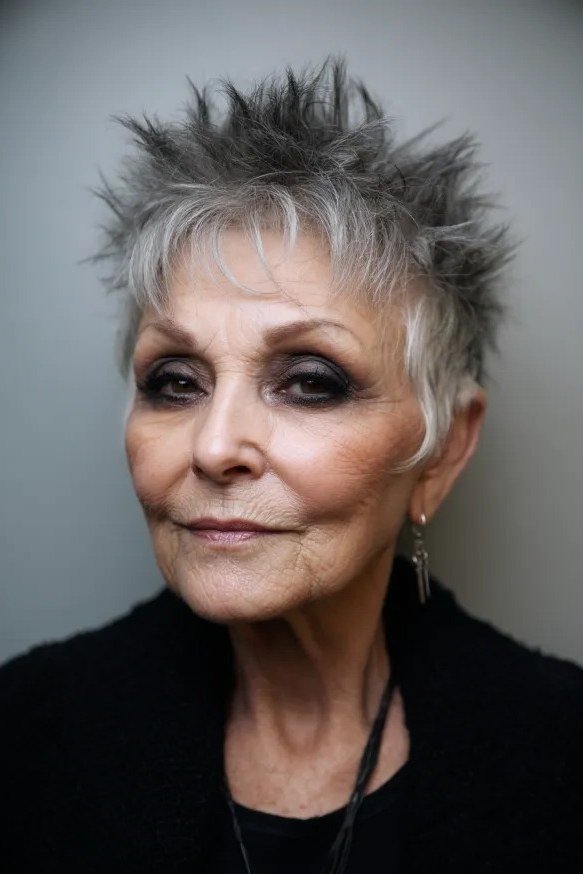 Grey pixie haircut for women over 50: silver spiky pixie, front view, dark background