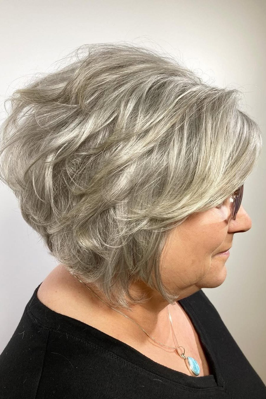 Wavy layered bob hairstyle for women over 50: silver wavy bob, side view, smooth waves