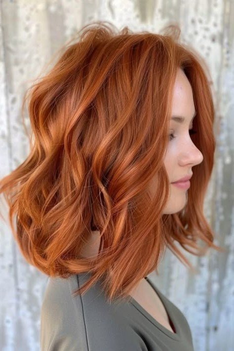 Wavy layered bob hairstyle for women over 50: copper wavy bob, side view, rich auburn