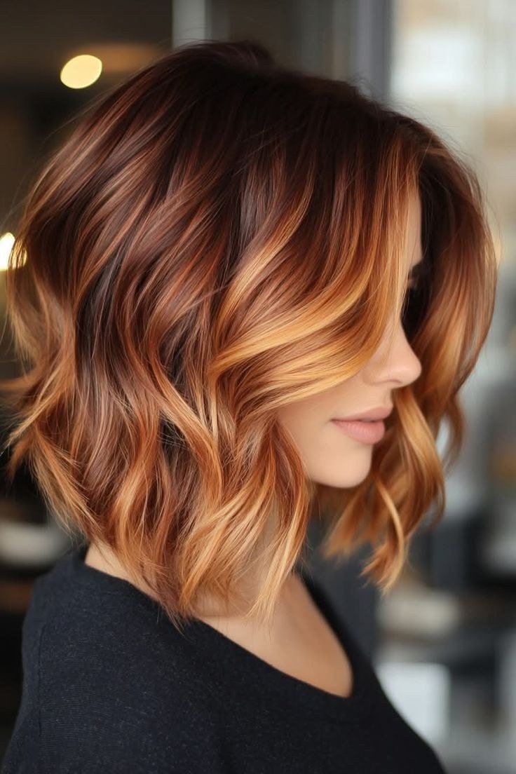 Wavy layered bob hairstyle for women over 50: copper balayage wavy bob, side view, dimensional red