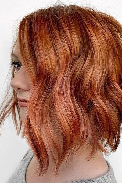 Wavy layered bob hairstyle for women over 50: copper wavy bob, side view, bright copper
