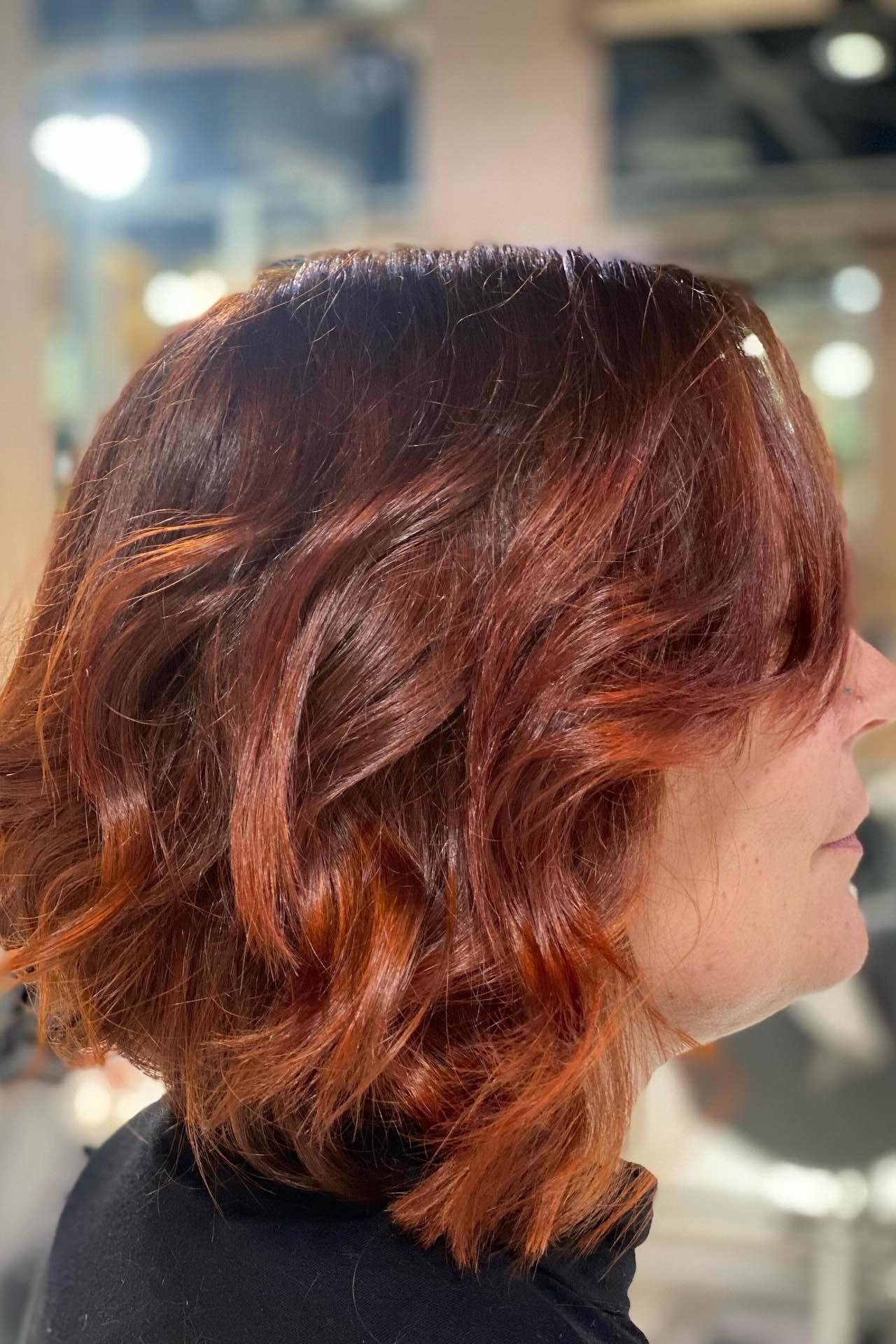 Wavy layered bob hairstyle for women over 50: copper wavy bob, side view, salon, deep red