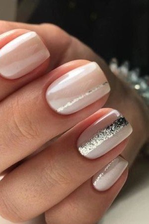 white almond nails with a silver glitter accent - honey glazed nude nails for women over 50