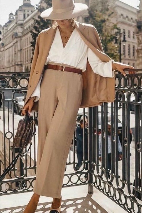 Woman over 50 wearing a camel blazer with fedora hat and wide-leg trousers, Italian style