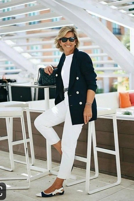 Woman over 50 in a black blazer with cropped white trousers and two-tone heels