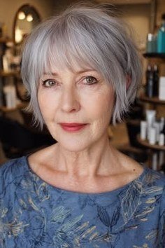 Senior woman with a tidy gray pixie haircut and soft full fringe.