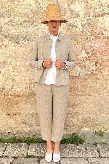 Woman over 50 in a beige jacket with straw hat and beige trousers, vacation style