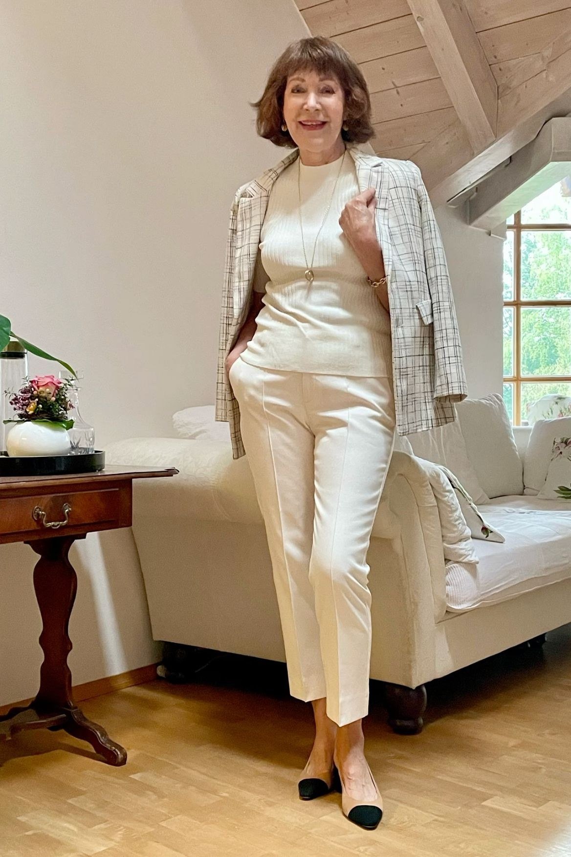 Woman over 50 in a champagne silk camisole with cream blazer and pearls