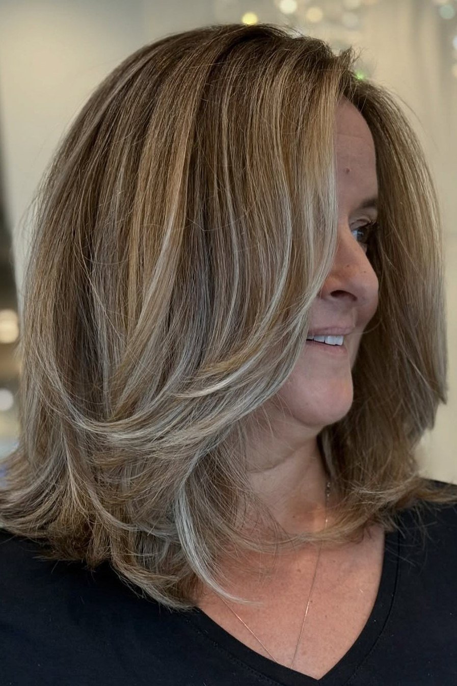 Highlighted layered medium hairstyle for women over 40, side view
