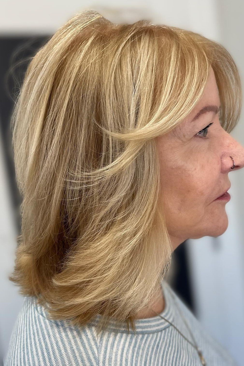 Blonde layered lob haircut for women over 40, side view