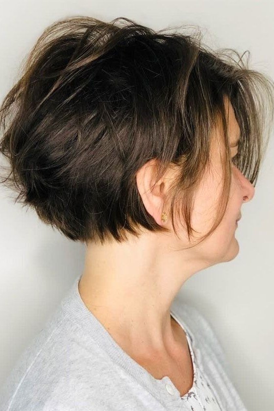 Side view of an older woman with a dark brown voluminous bixie haircut.