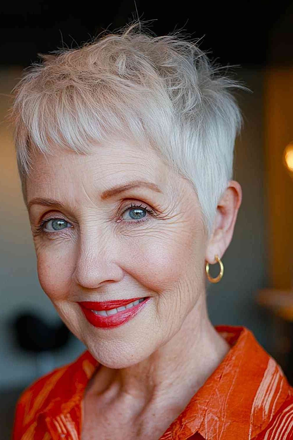 Senior woman with a white pixie haircut and bold red lipstick.