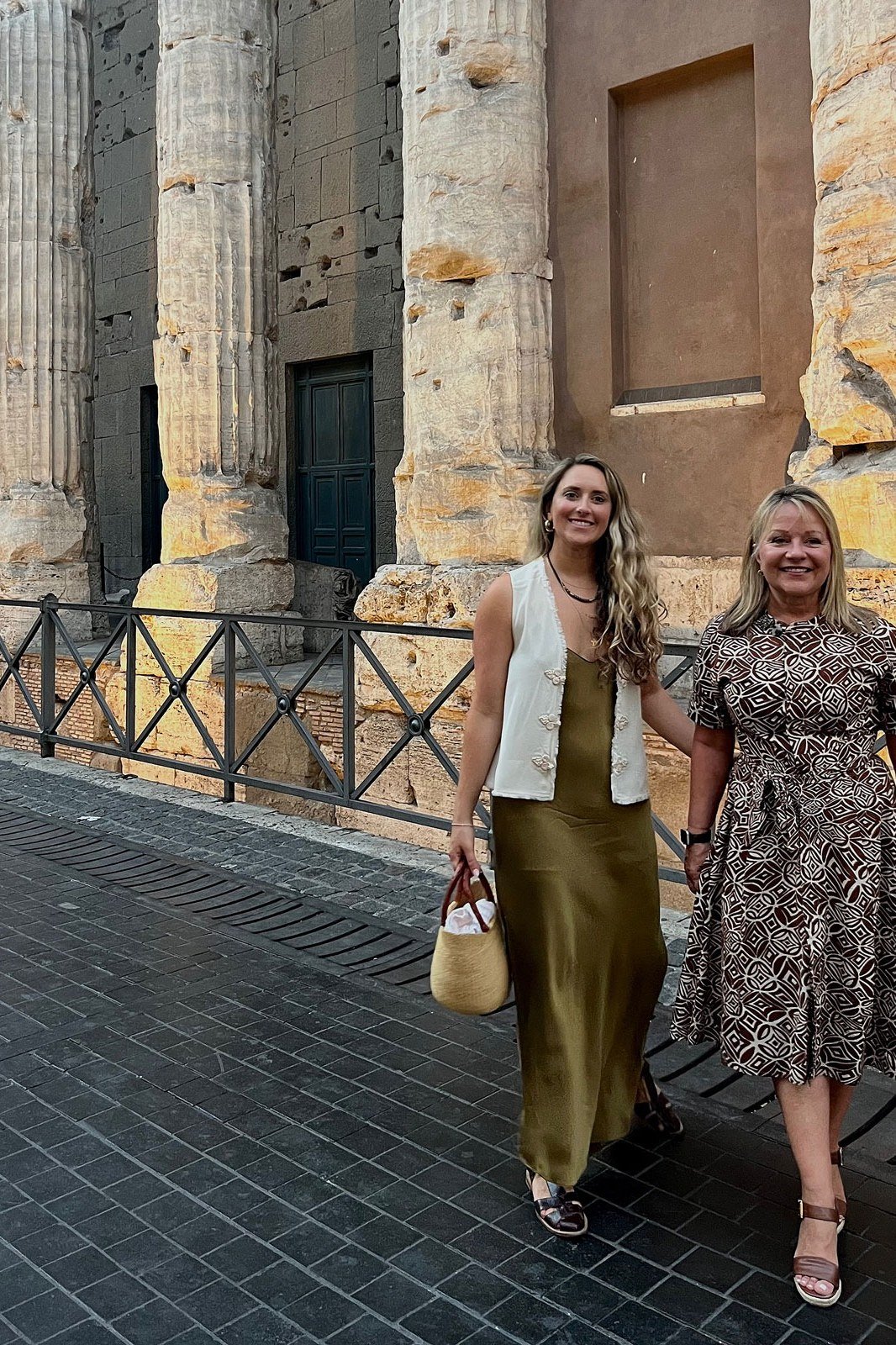 Two friends over 50 strolling in an olive slip dress and a gray midi dress, Italian style
