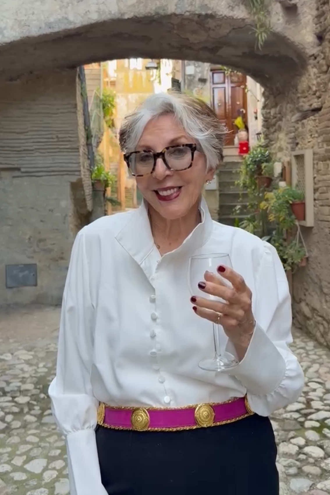 Woman over 50 in a white blouse with navy skirt and colorful striped belt