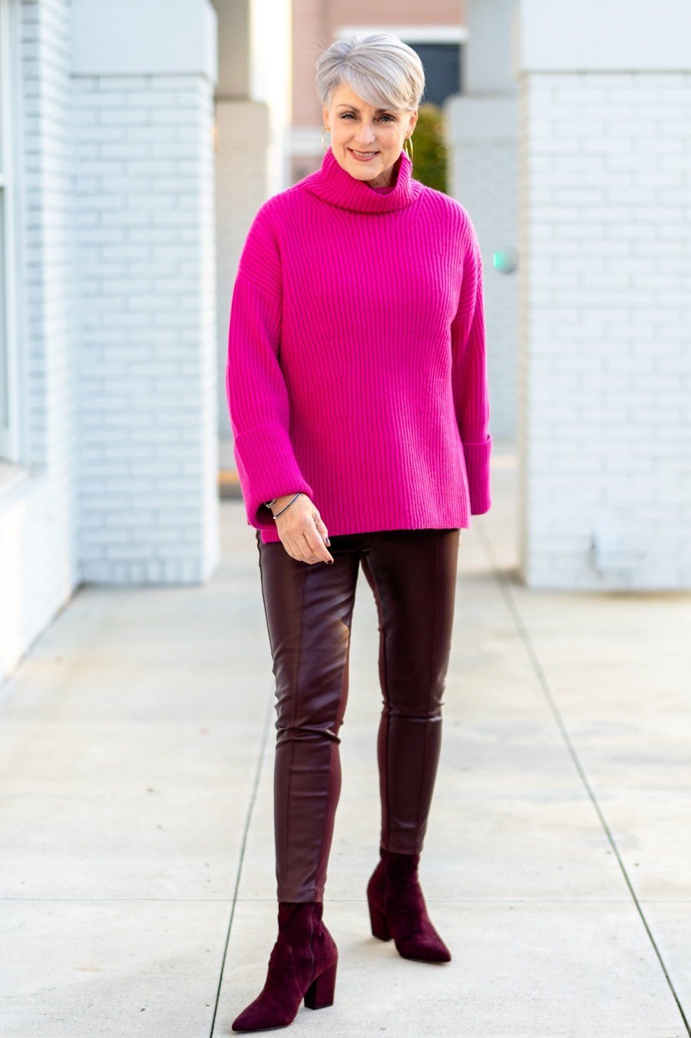 Thanksgiving outfit for women over 50: fuchsia turtleneck with burgundy leather pants