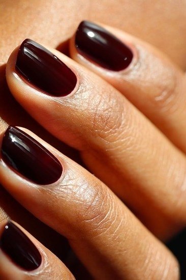 Glossy cherry cola squoval nails close up on mature hand