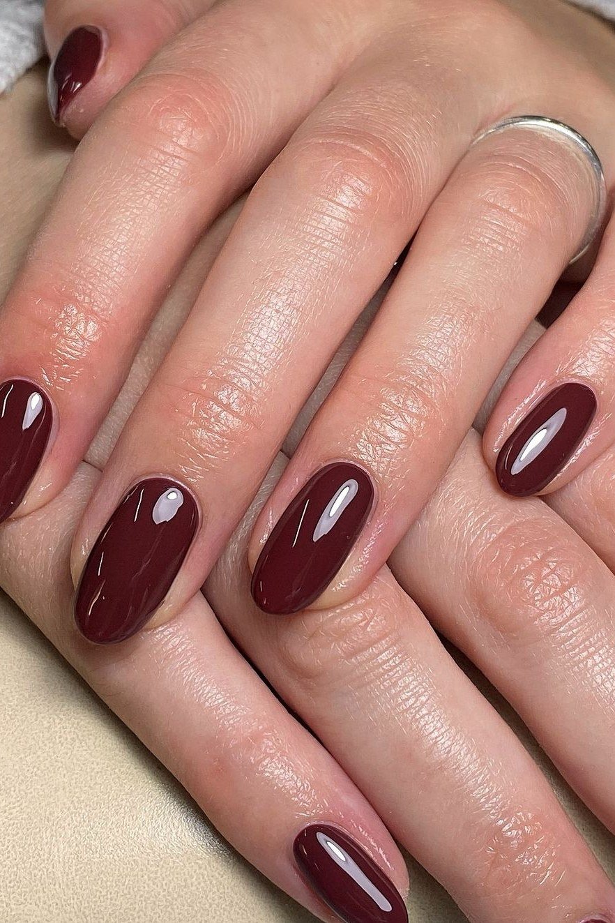 Glossy black cherry squoval nails on mature hands
