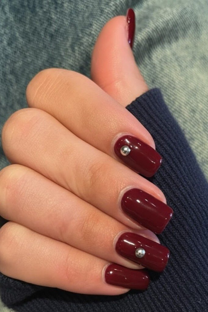 Cranberry red short oval nails with rhinestone accent