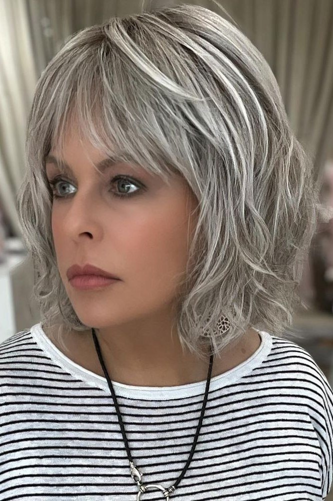 Wispy silver-grey layered bob with feathered bangs in three-quarter view