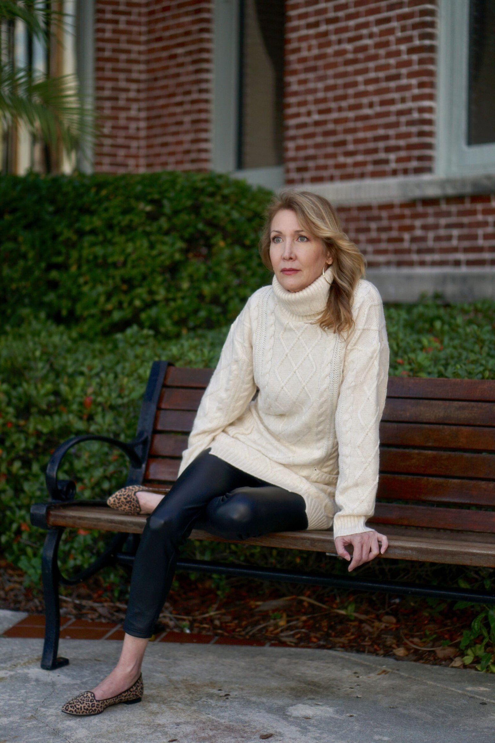 Cream turtleneck sweater, black leggings, flats, park bench, leggings outfit idea for women over 50