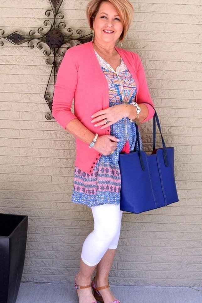 Pink cardigan over patterned tunic, white capri leggings, pink sandals, leggings outfit idea for women over 50