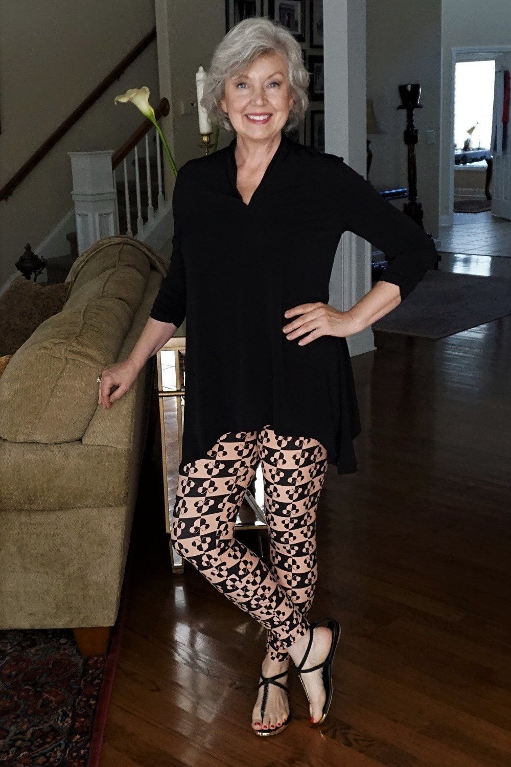 Black tunic, geometric black-and-cream clover-print leggings, strappy sandals, leggings outfit idea for women over 50