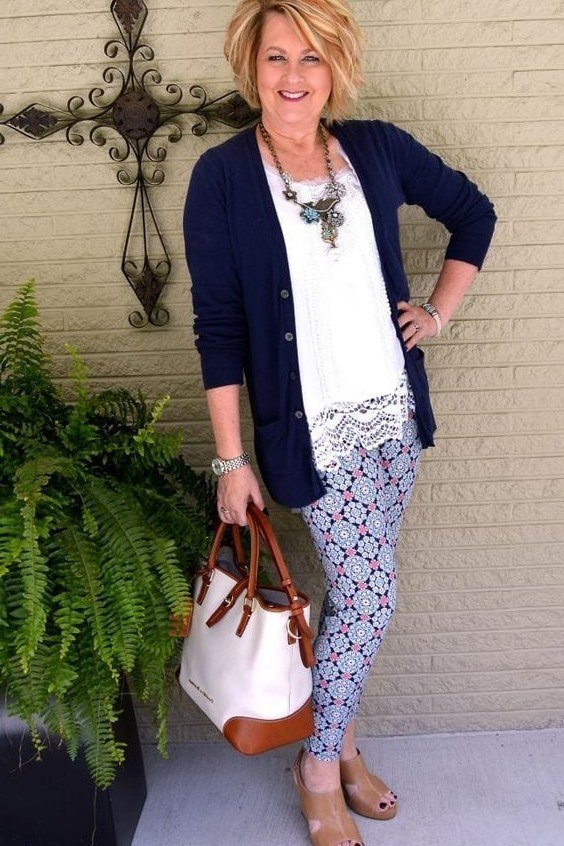 Navy cardigan over white top, blue patterned leggings, tan handbag, leggings outfit idea for women over 50
