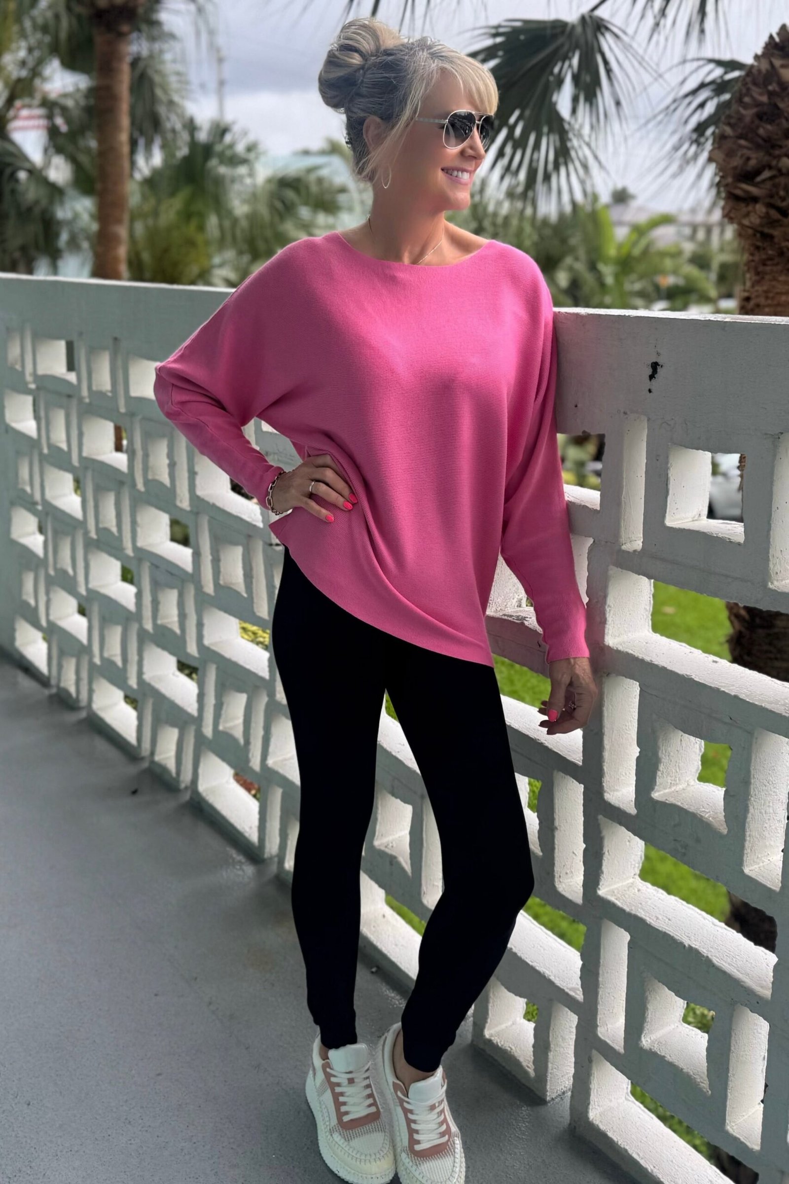 Hot-pink sweater, black leggings, white sneakers, balcony, leggings outfit idea for women over 50