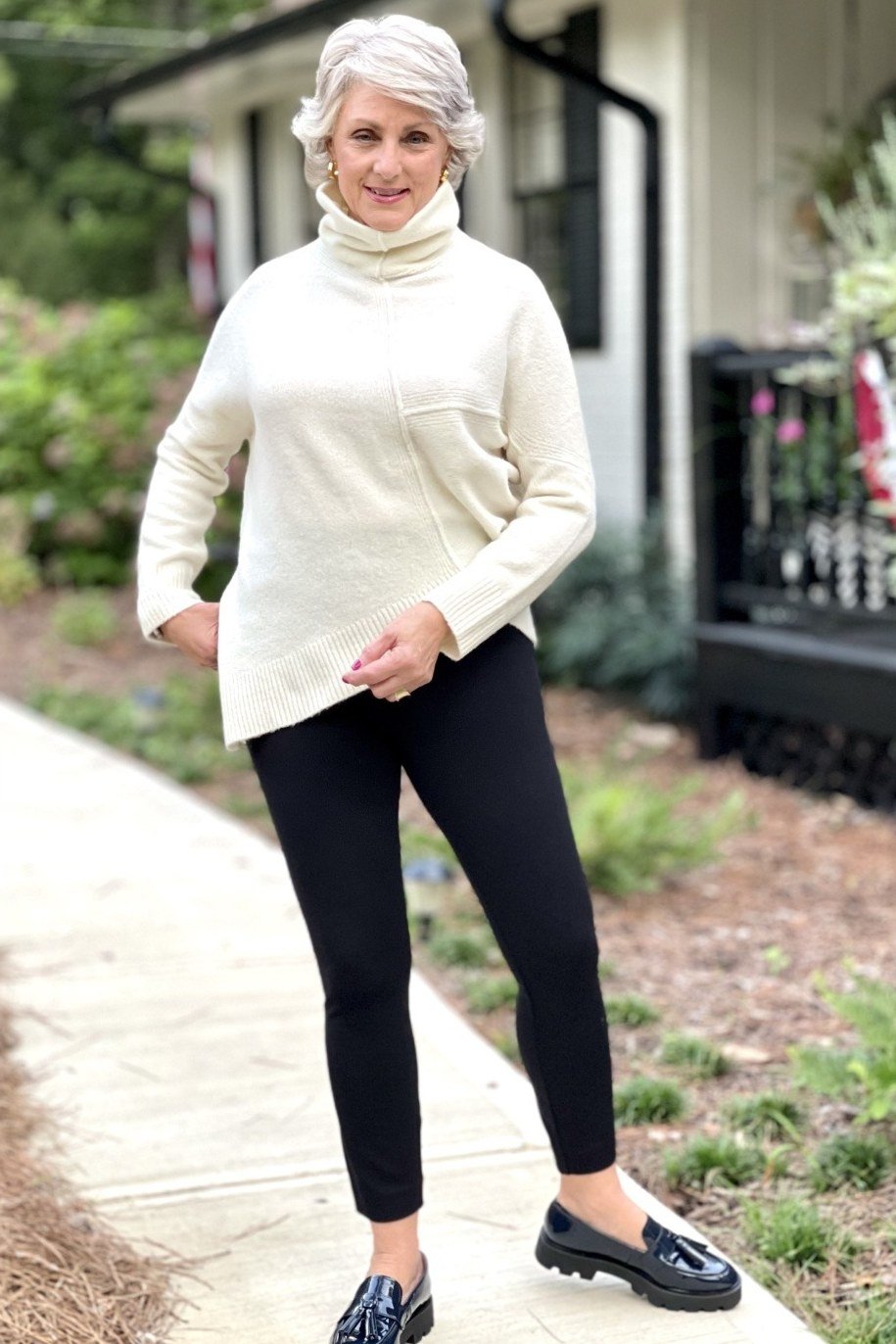 Cream turtleneck, black leggings, black loafers, driveway, leggings outfit idea for women over 50