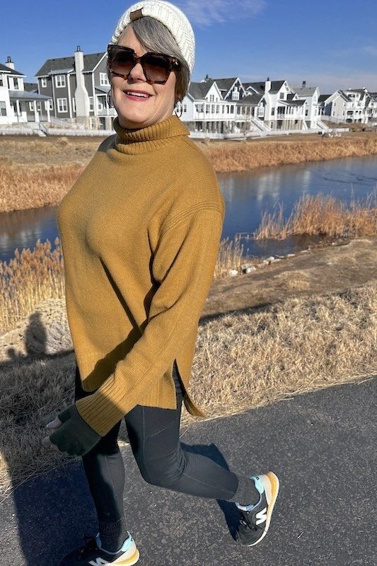 Mustard turtleneck, black leggings, sneakers, waterfront path, leggings outfit idea for women over 50