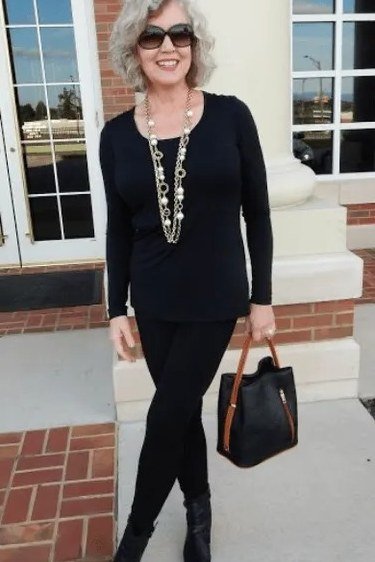Black tunic, black leggings, long necklace, brick porch, leggings outfit idea for women over 50