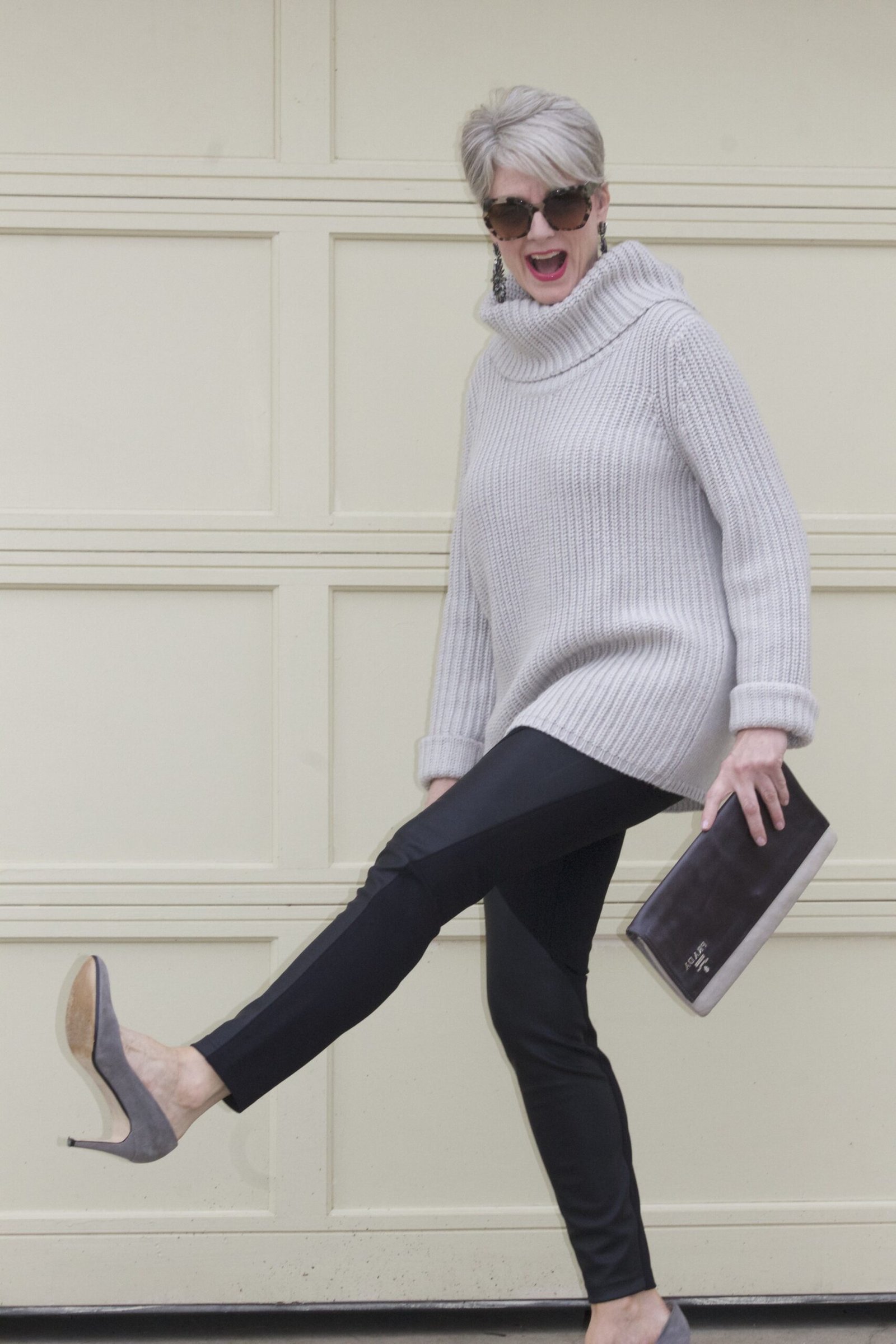 Gray turtleneck, black leggings, gray heels, playful kick pose, leggings outfit idea for women over 50